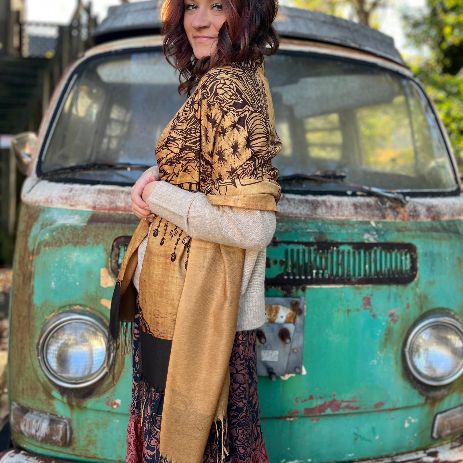 A woman wrapped up in the Cats Under The Stars Pashmina in front of a teal Volkswagen bus.