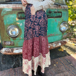 Someone wearing the  witCactus Garden Tiered Maxi Skirt a beige skirt in front of a vintage Volkswagen bus, showing off the side.