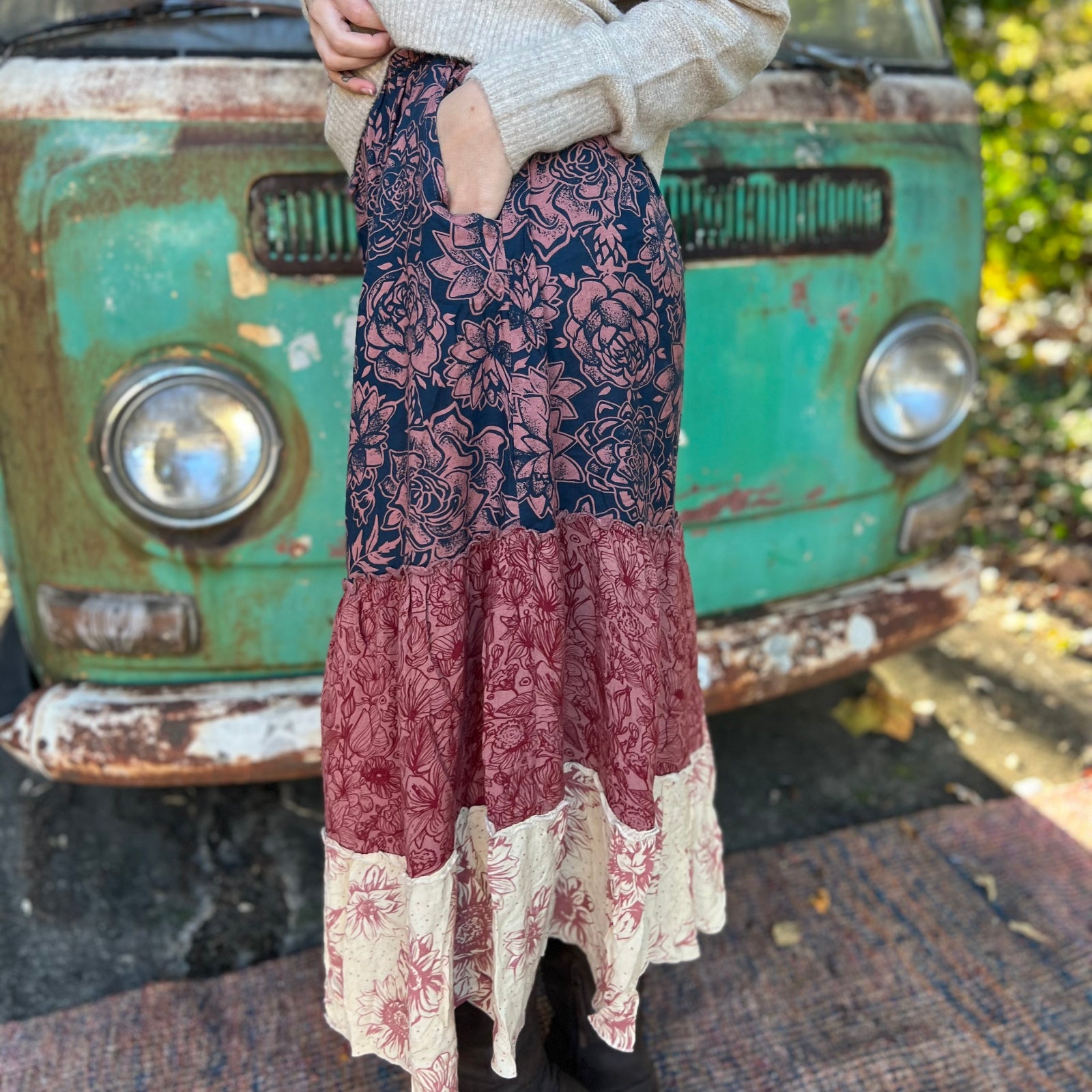 Someone wearing the  witCactus Garden Tiered Maxi Skirt a beige skirt in front of a vintage Volkswagen bus, showing off the side.