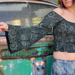 A woman wearing the forest Flowy Peasant Viscose Print Blouse with a skirt in front of the vintage teal Volkswagen bus.