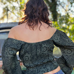 A woman wearing the forest Flowy Peasant Viscose Print Blouse with a skirt in front of the vintage teal Volkswagen bus, showing off the back.