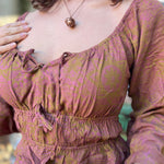 A woman wearing the maroon Flowy Peasant Viscose Print Blouse with a skirt in front of the vintage teal Volkswagen bus.