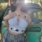 A woman wearing the Moon Cycle Crochet Halter Cotton Top with a skirt in front of a vintage teal Volkswagen bus.