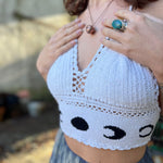 A woman wearing the Moon Cycle Crochet Halter Cotton Top with a skirt in front of a vintage teal Volkswagen bus.