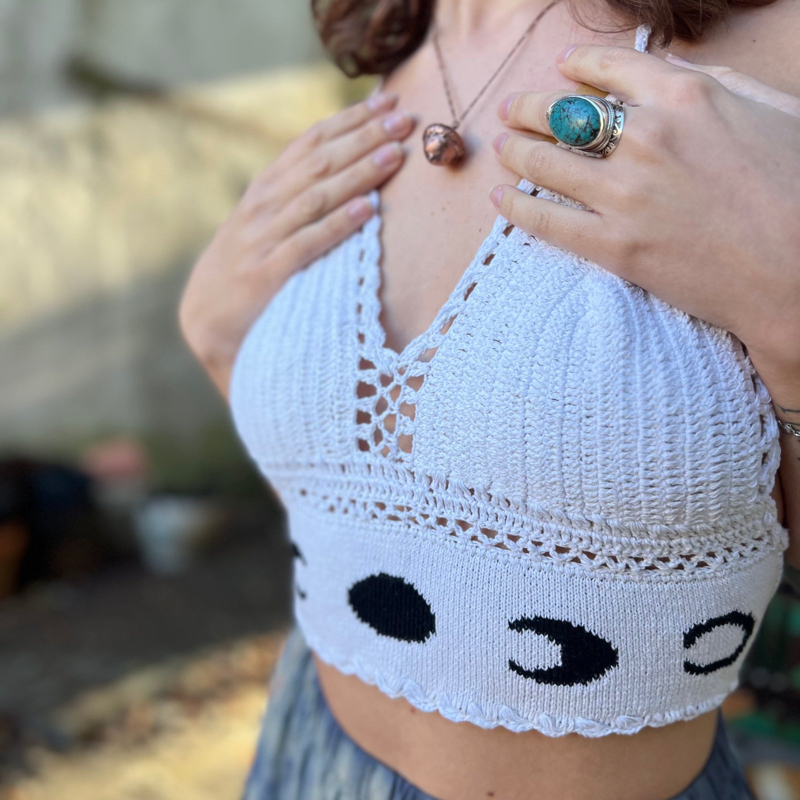 A woman wearing the Moon Cycle Crochet Halter Cotton Top with a skirt in front of a vintage teal Volkswagen bus.