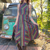 A woman wearing the olive Striped Twirl Skirt Cotton Overall with brown boots in front of a vintage teal Volkswagen bus.