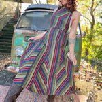 A woman wearing the olive Striped Twirl Skirt Cotton Overall with brown boots in front of a vintage teal Volkswagen bus.