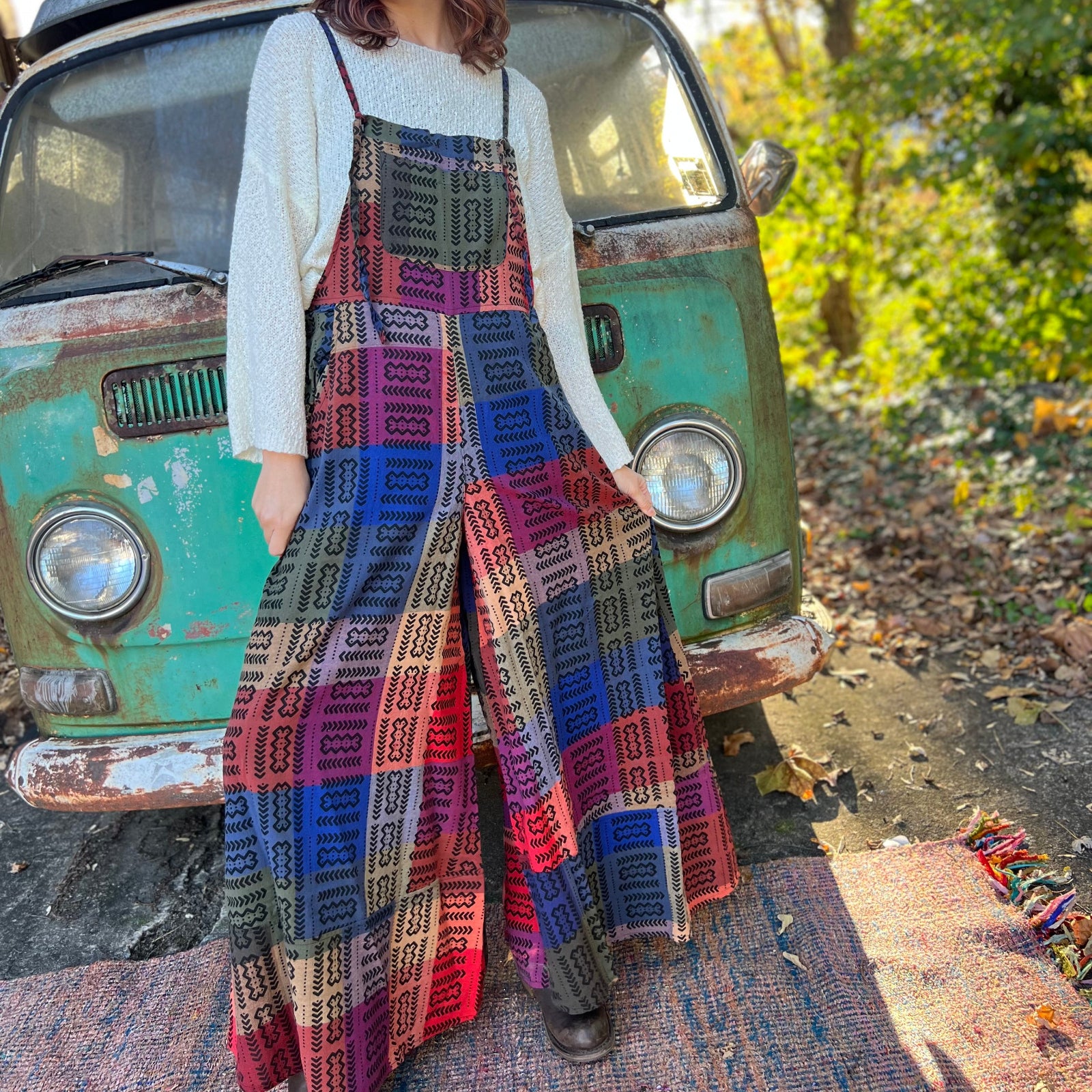 A woman wearing the Cotton Plaid Wide Leg Overalls with a white long sleeve in front of a vintage teal Volkswagen bus.
