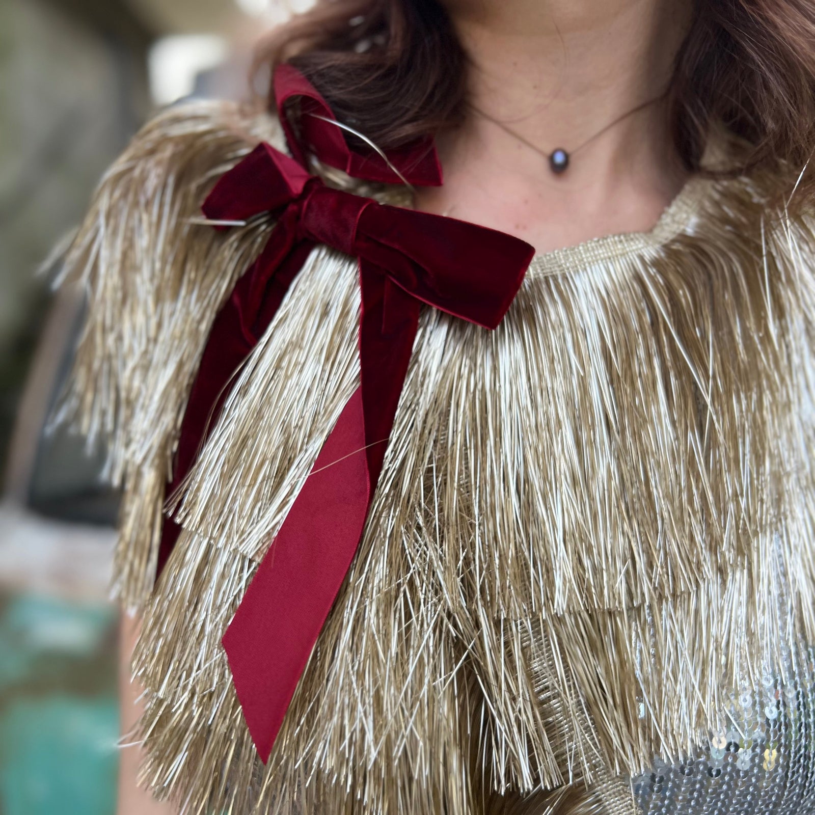 Someone wearing the Gilded Bow Gold Layered Fringe Banner in front of a vintage teal Volkswagen bus.