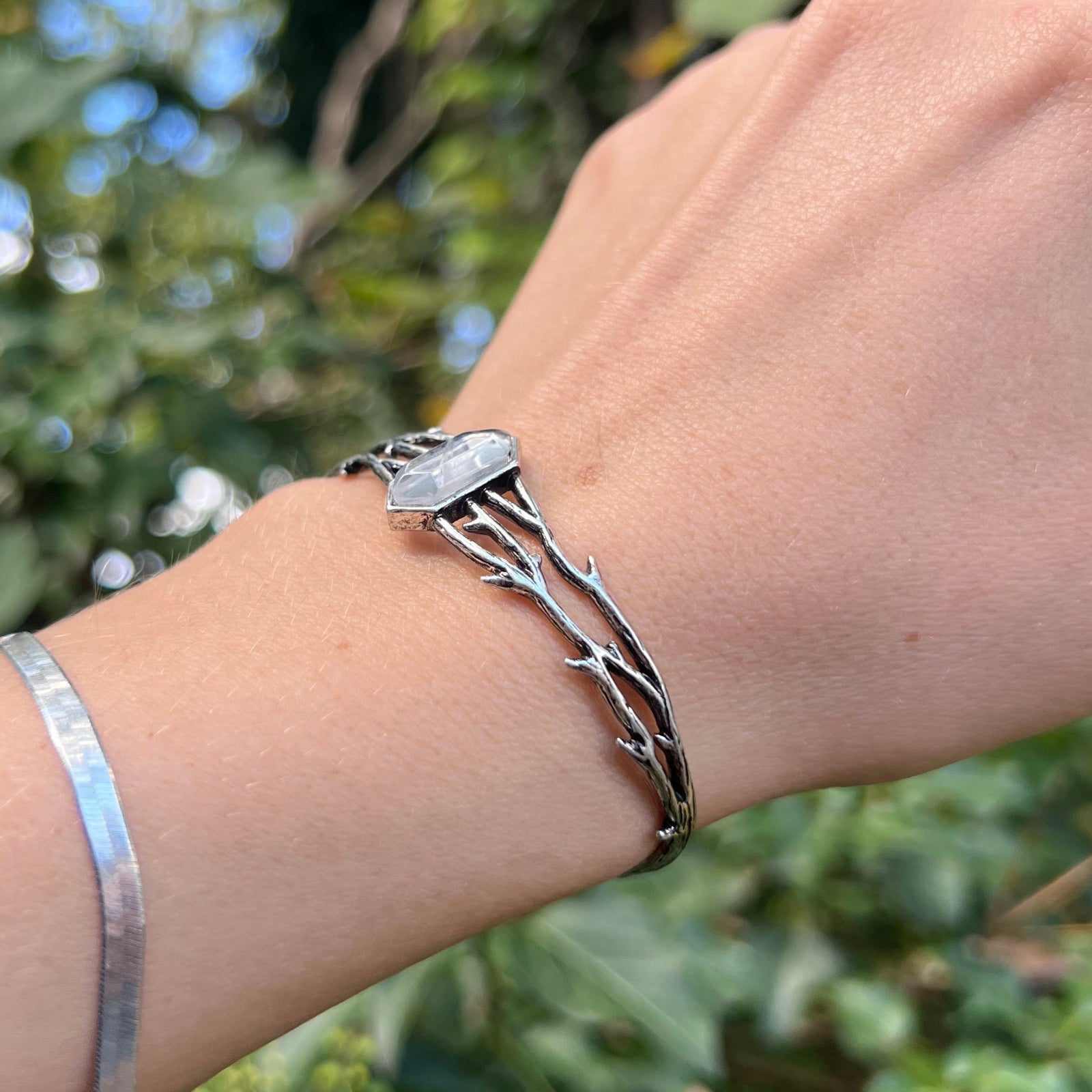 Someone wearing the Silver Thorn Cuff Bracelet in front of a green bush.