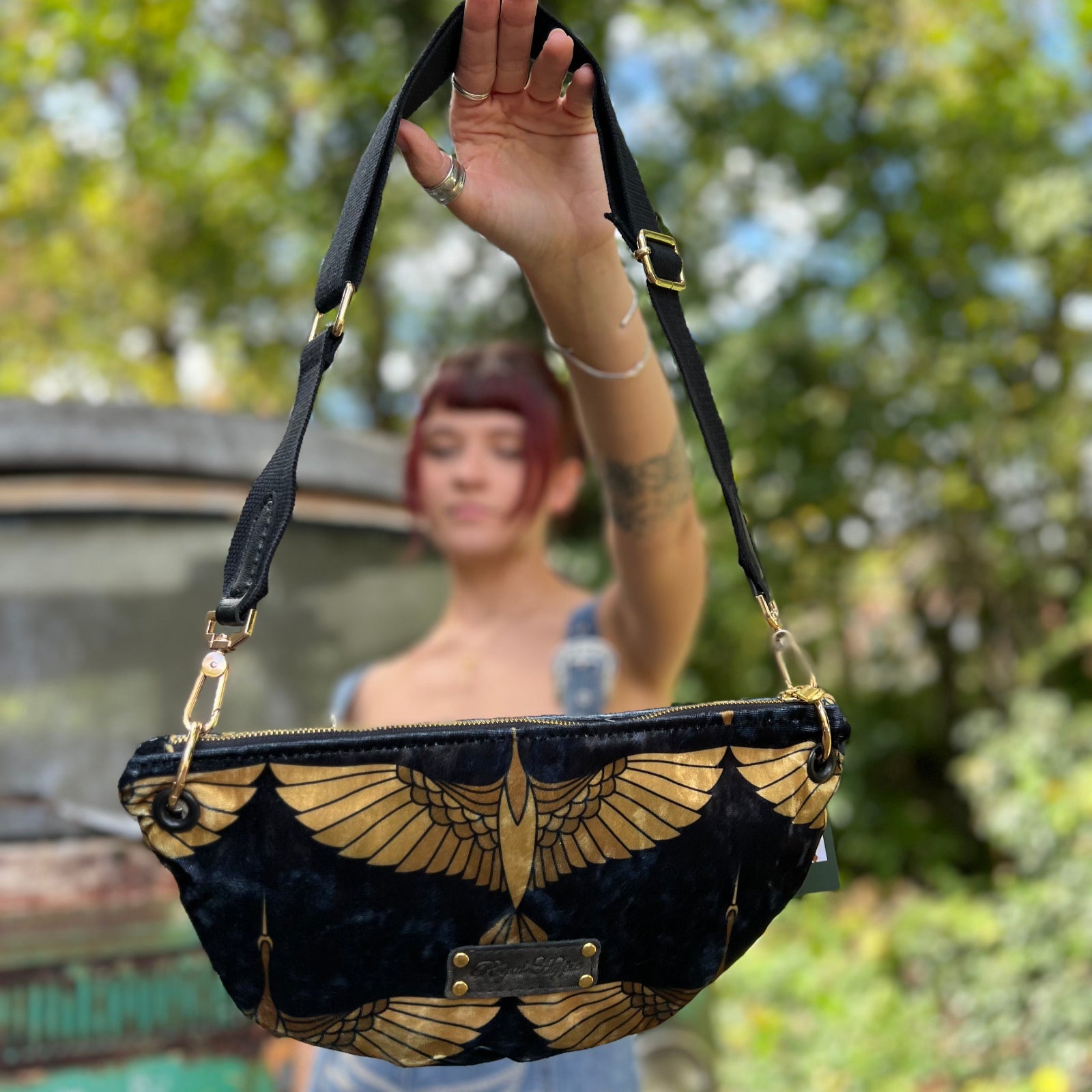Someone holding the Black And Gold Heron Fanny Bag out in front of them.