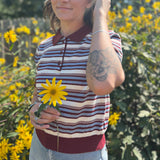 A woman wearing the Striped Knit Sweater Half Button Up Collar Top with some jeans on, in front of some greenery.
