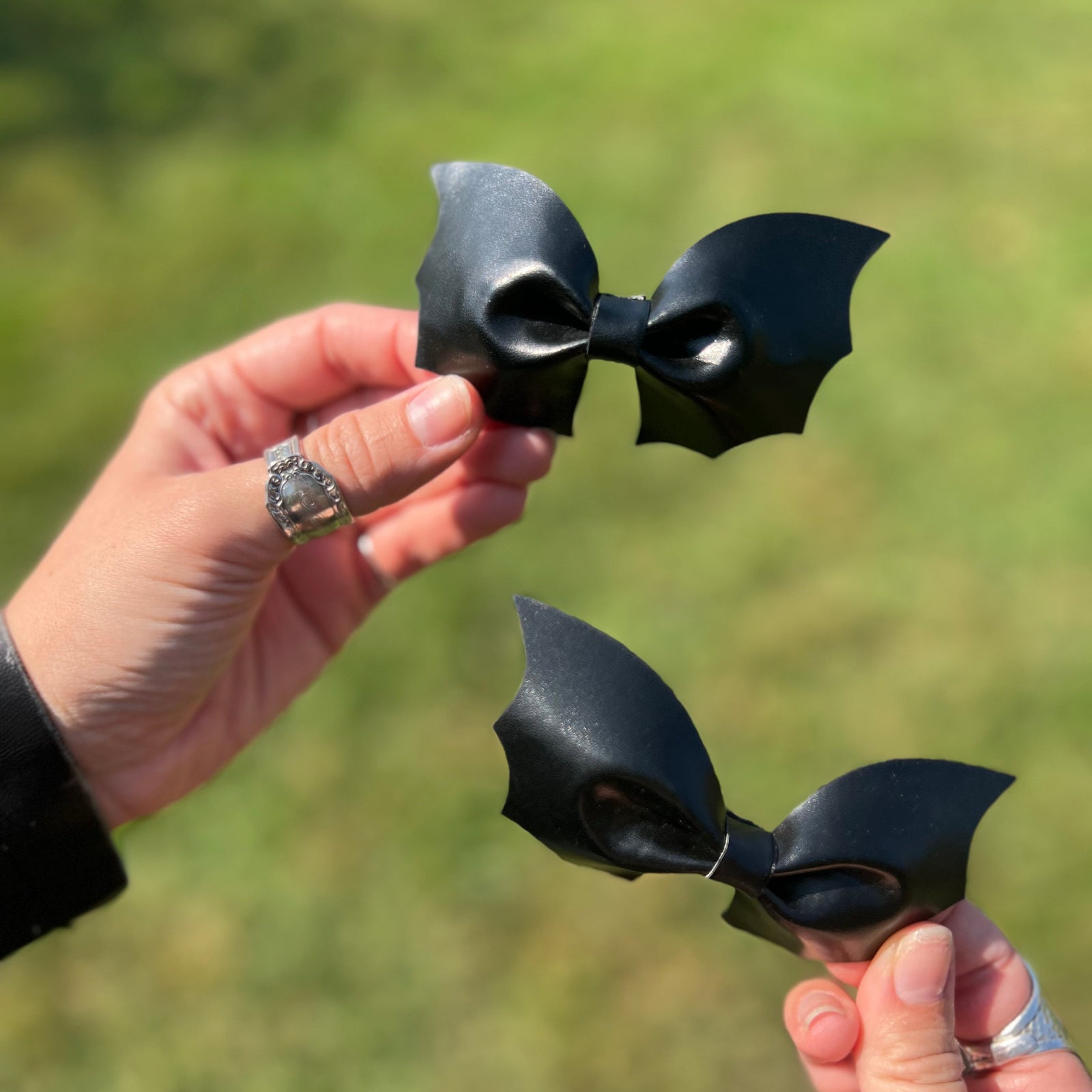 A woman holding two Leather Bat Halloween Hair Clips.