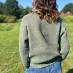 A woman wearing the Horse Embroidery Knit Pullover Sweater with the denim pants, showing off the back.