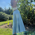 A woman wearing the light wash Denim Drawstring Waist Band Wide Leg Pants with a cream crocheted top.