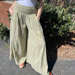 A woman wearing the sage Striped Wide Leg Cotton Pants with a white top and sandals.