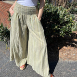 A woman wearing the sage Striped Wide Leg Cotton Pants with a white top and sandals.