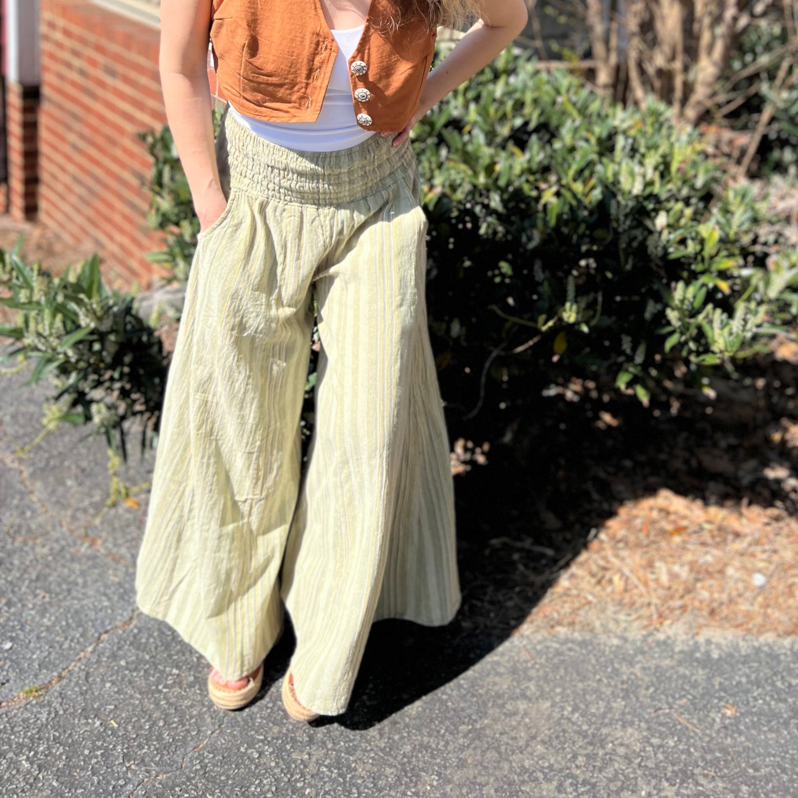A woman wearing the sage Striped Wide Leg Cotton Pants with a white top and sandals.