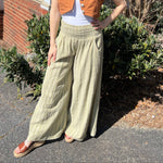 A woman wearing the sage Striped Wide Leg Cotton Pants with a white top and sandals.