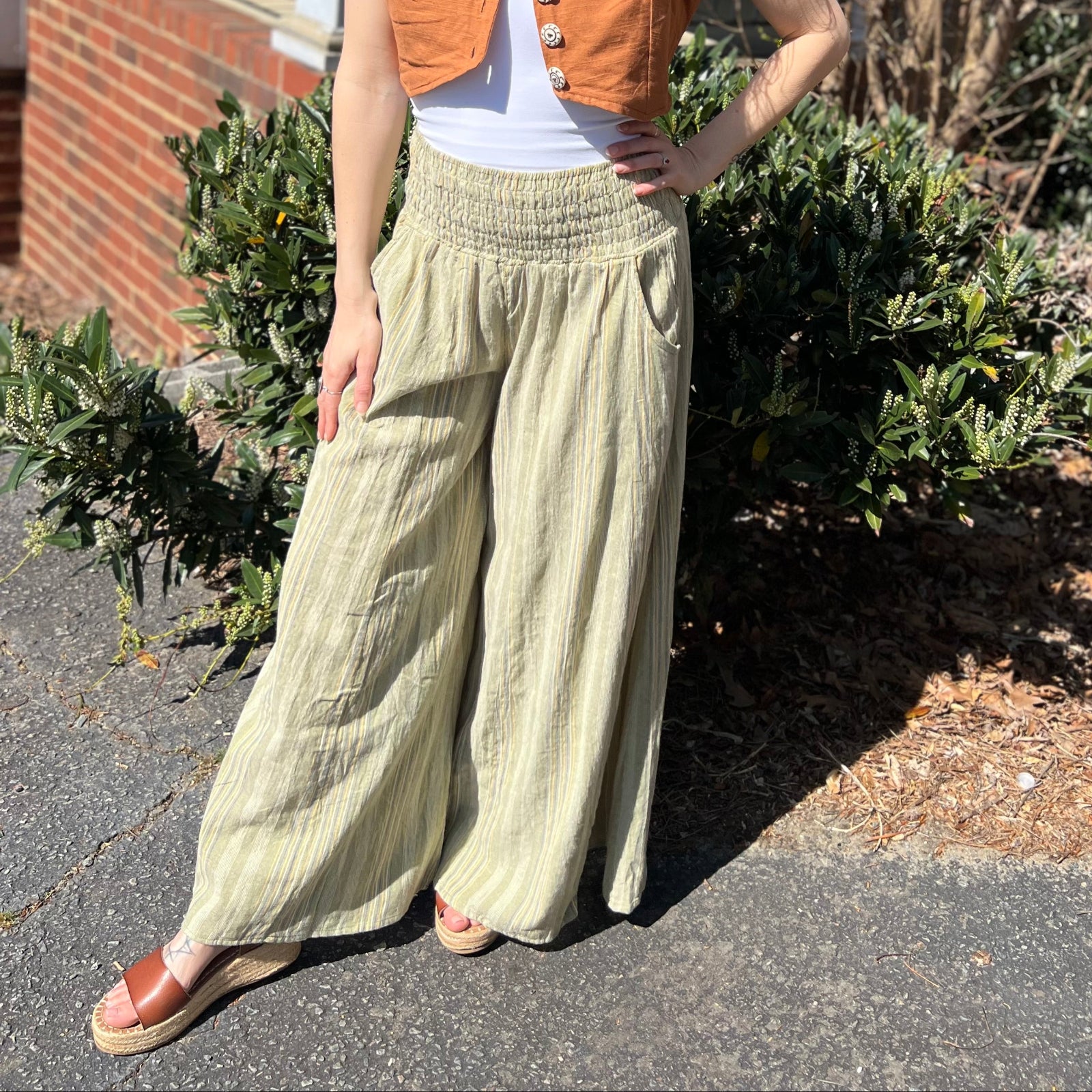 A woman wearing the sage Striped Wide Leg Cotton Pants with a white top and sandals.