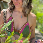 A woman wearing the sage Festive Crochet Top: One Size with patchwork overalls and an evil eye necklace.