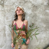 A woman wearing the sage Festive Crochet Top: One Size with patchwork overalls and an evil eye necklace.