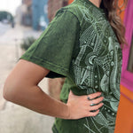 A woman wearing the Green Moon Mushroom Stonewash T-shirt in front of a brick wall.