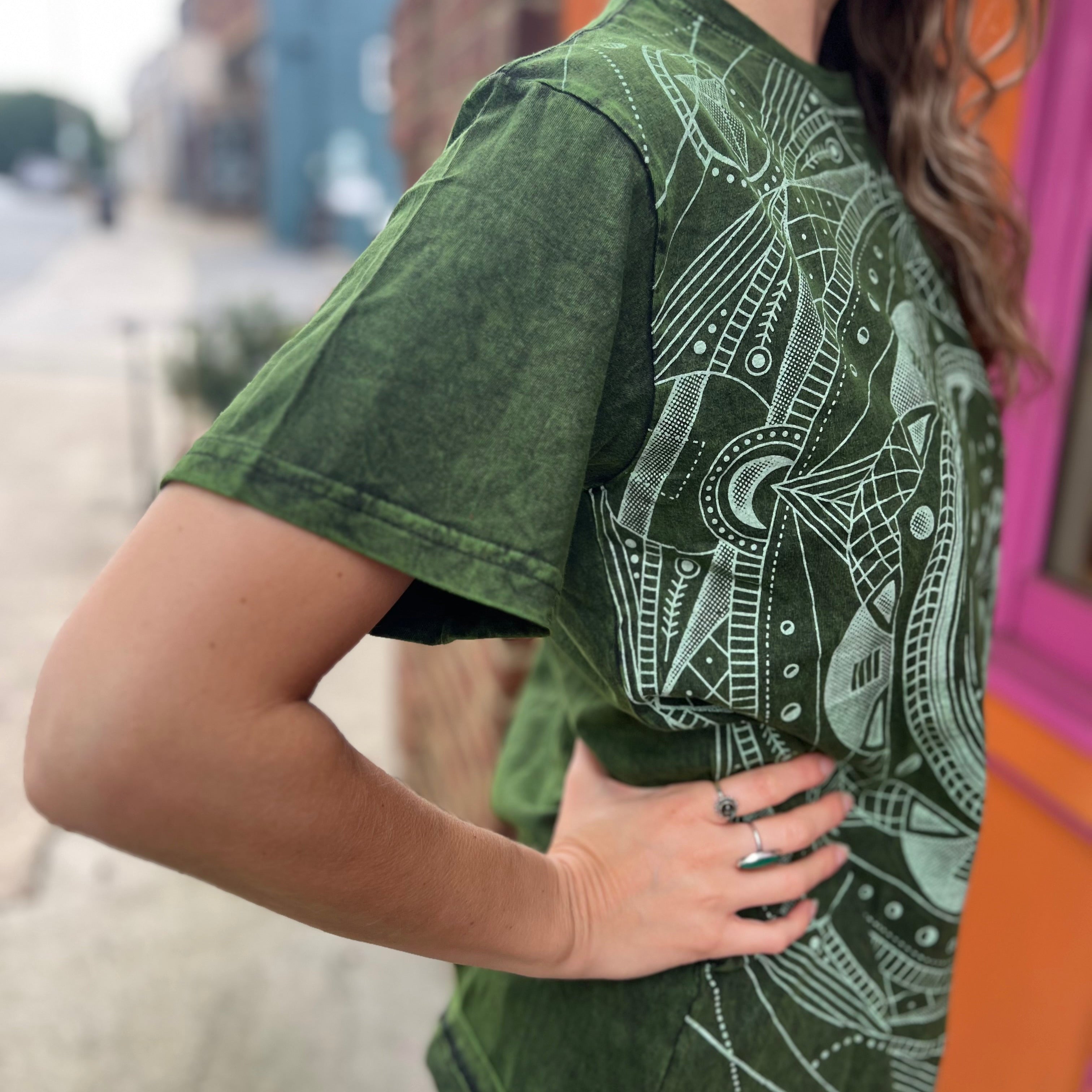 A woman wearing the Green Moon Mushroom Stonewash T-shirt in front of a brick wall.