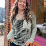 A woman wearing the green Hollow Out Knit Drop Sleeve Sweater in front of a pink and orange wall.