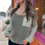 A woman wearing the green Hollow Out Knit Drop Sleeve Sweater in front of a pink and orange wall.