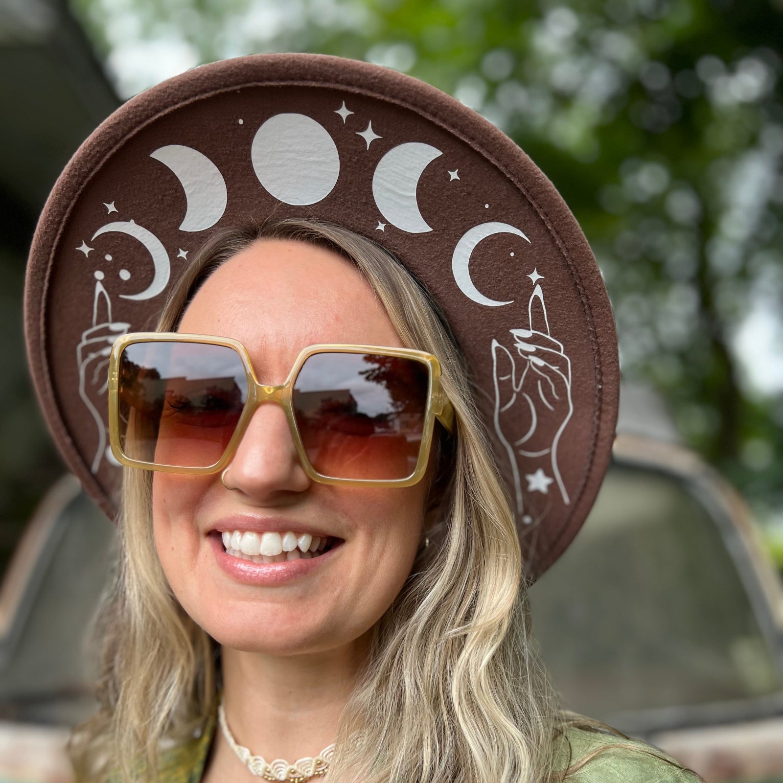 A woman wearing the olive Kelso 70s Sunglasses with a brown hat and green. kimono.