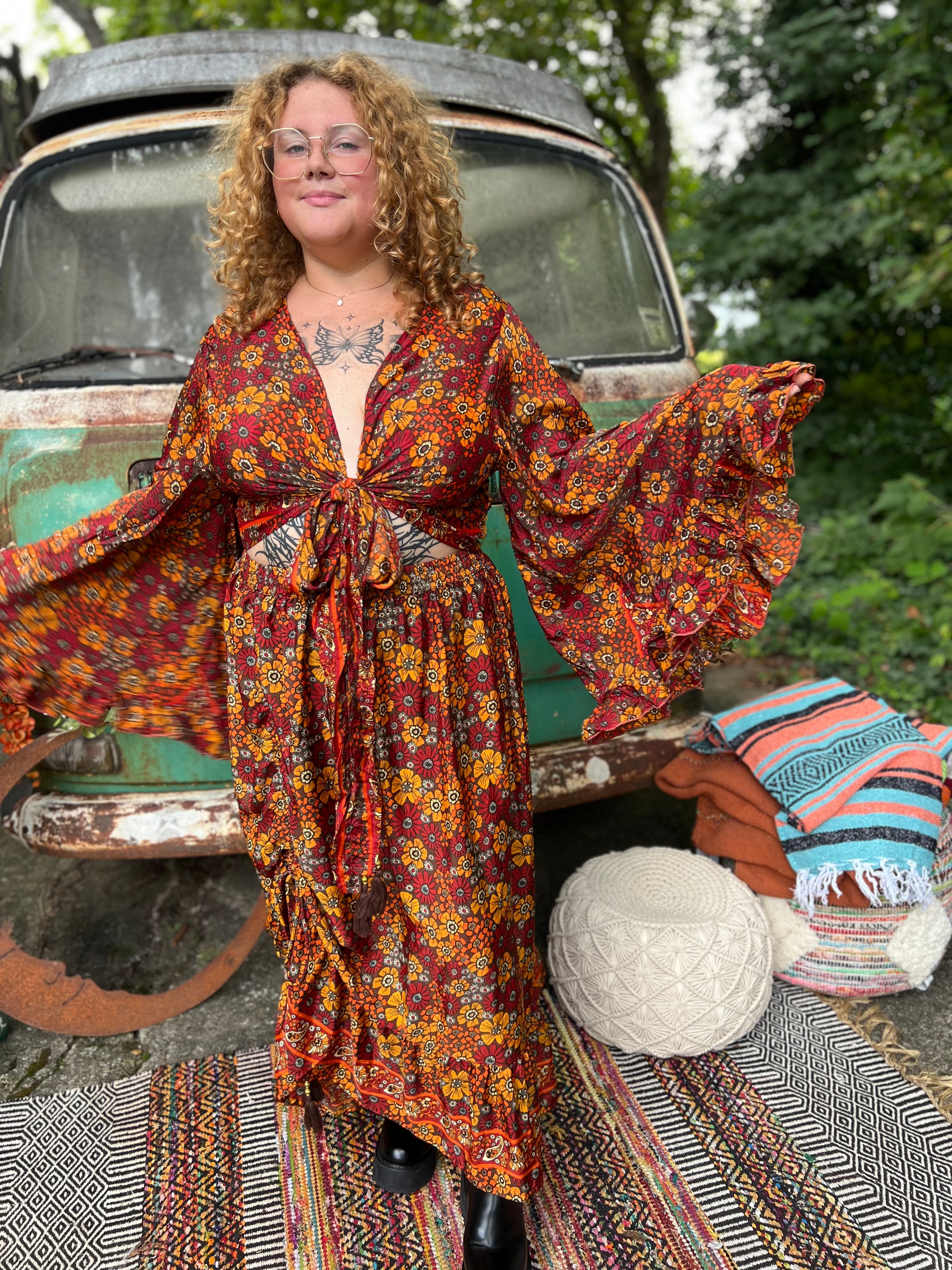 Someone wearing the red Hippie Floral Cinch Maxi Ruffle Skirt in front of a Volkswagen bus.