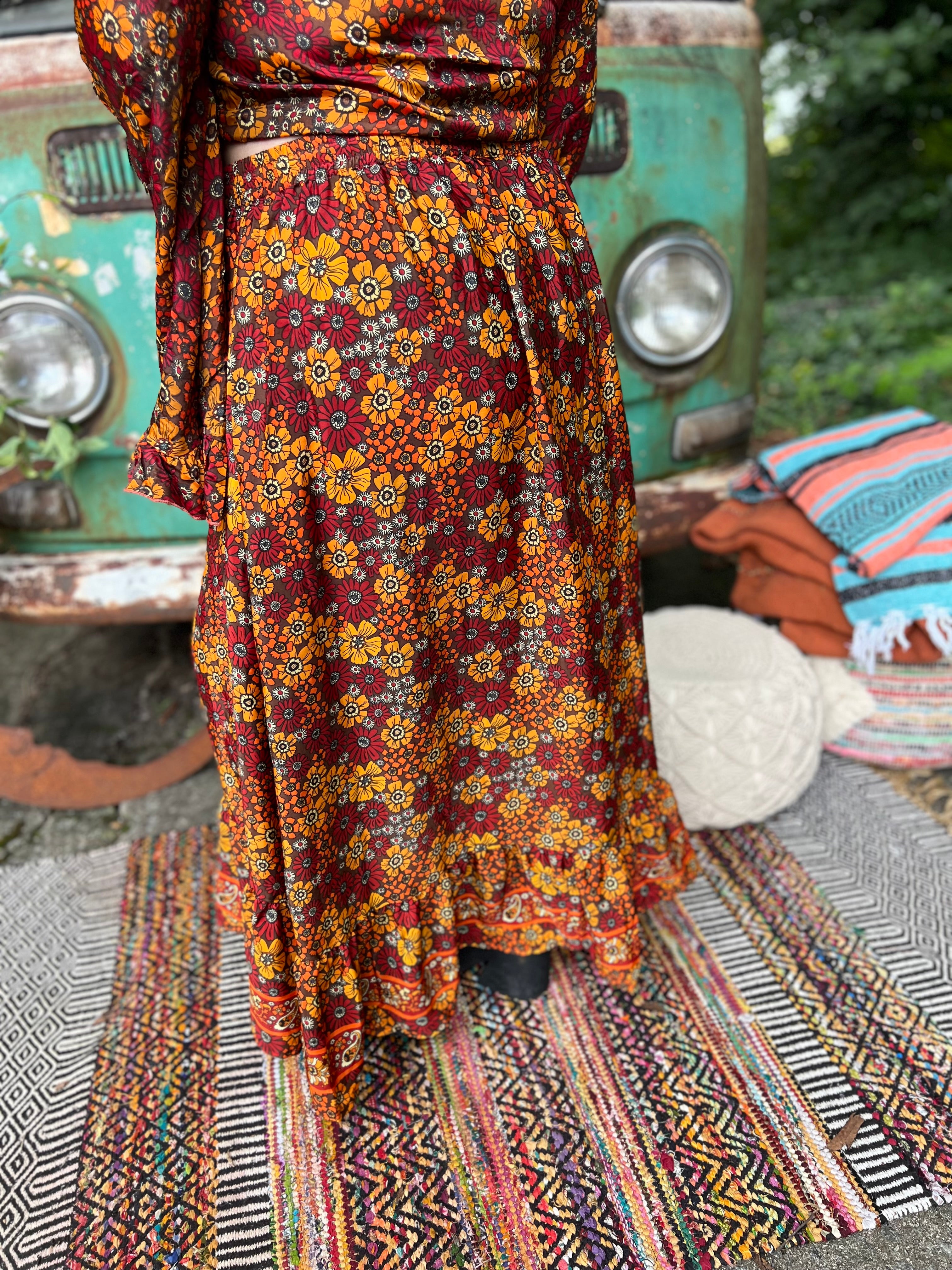 Someone wearing the red Hippie Floral Cinch Maxi Ruffle Skirt in front of a Volkswagen bus.