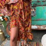 Someone wearing the red Hippie Floral Cinch Maxi Ruffle Skirt in front of a Volkswagen bus.