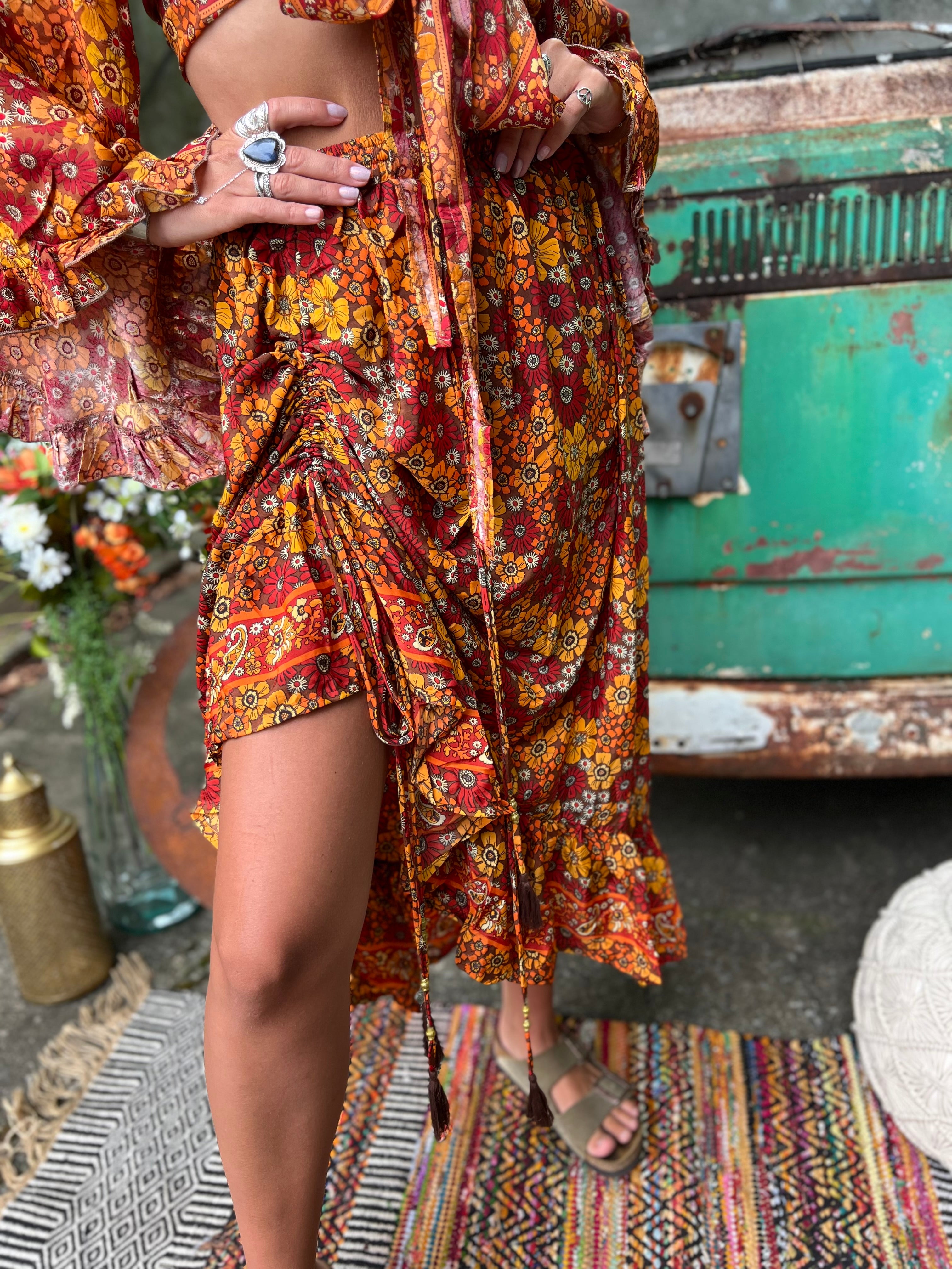 Someone wearing the red Hippie Floral Cinch Maxi Ruffle Skirt in front of a Volkswagen bus.