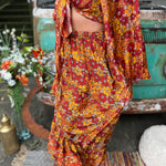 Someone wearing the red Hippie Floral Cinch Maxi Ruffle Skirt in front of a Volkswagen bus.