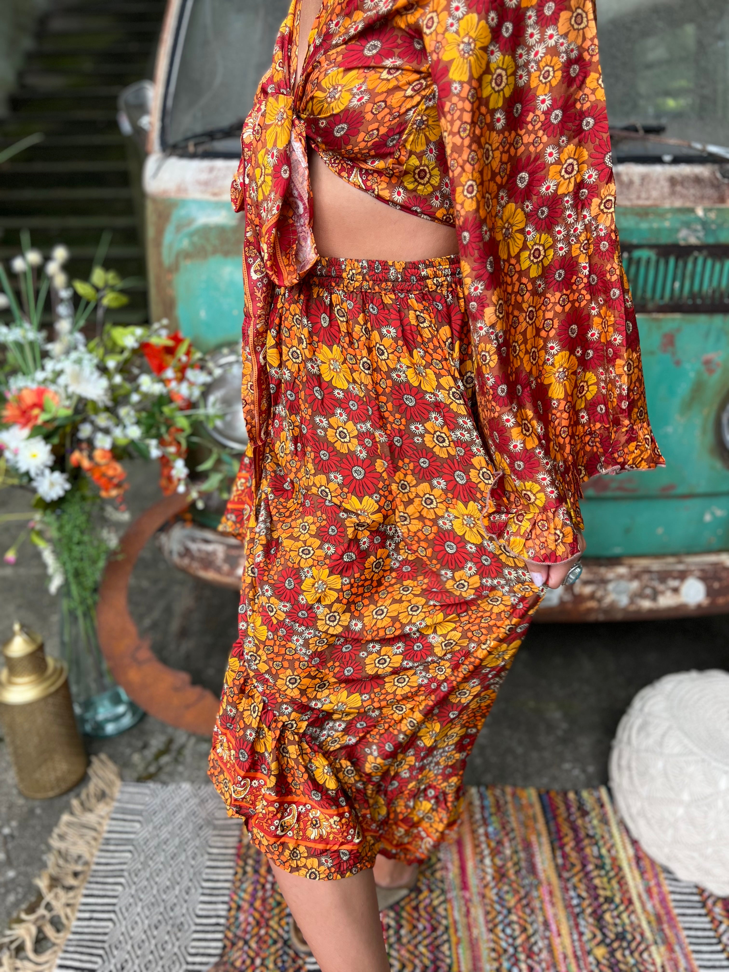 Someone wearing the red Hippie Floral Cinch Maxi Ruffle Skirt in front of a Volkswagen bus.