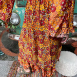 Someone wearing the red Hippie Floral Cinch Maxi Ruffle Skirt in front of a Volkswagen bus.