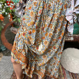 Someone wearing the orange & cream Hippie Floral Cinch Maxi Ruffle Skirt in front of a Volkswagen bus.