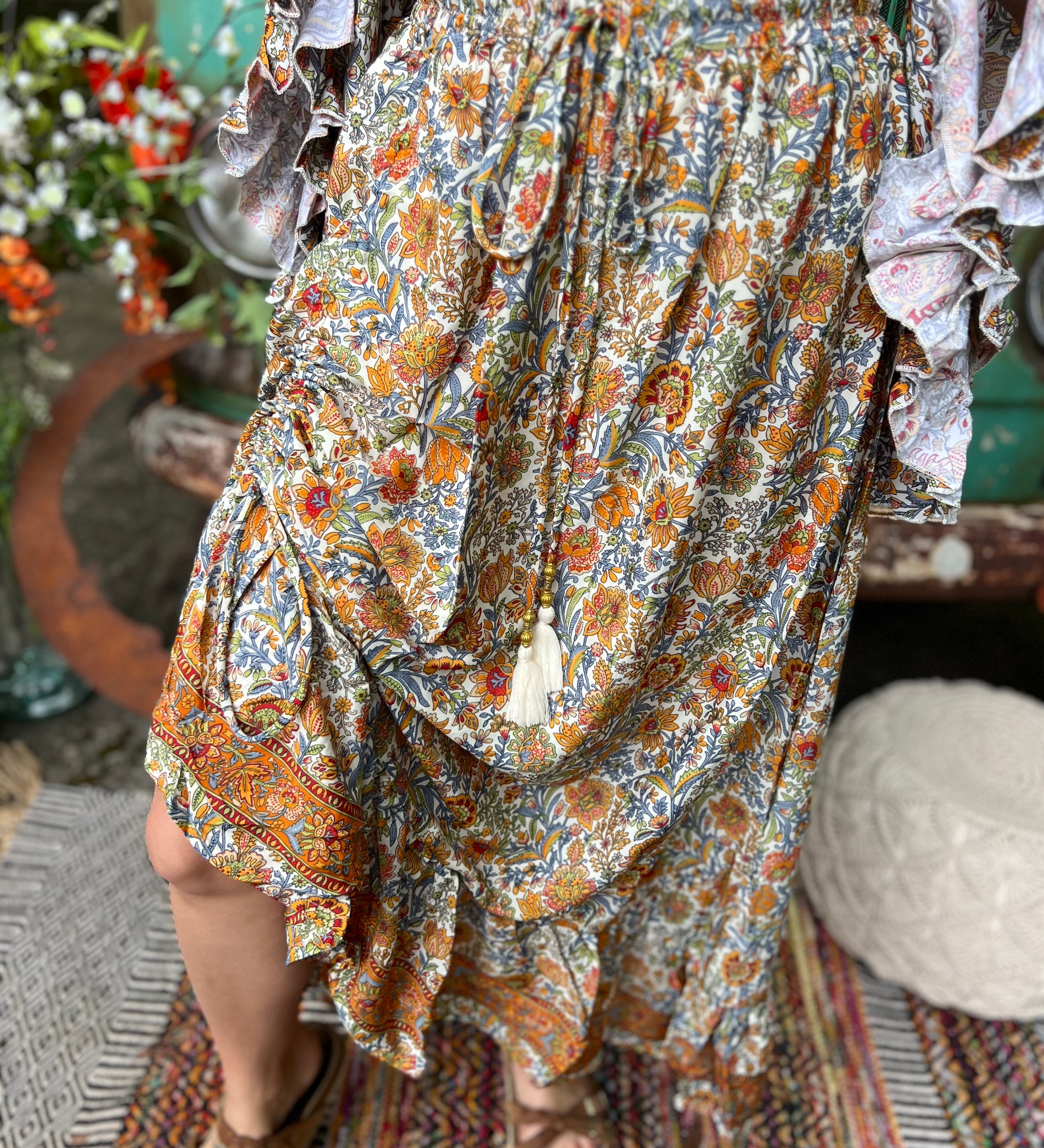 Someone wearing the orange & cream Hippie Floral Cinch Maxi Ruffle Skirt in front of a Volkswagen bus.