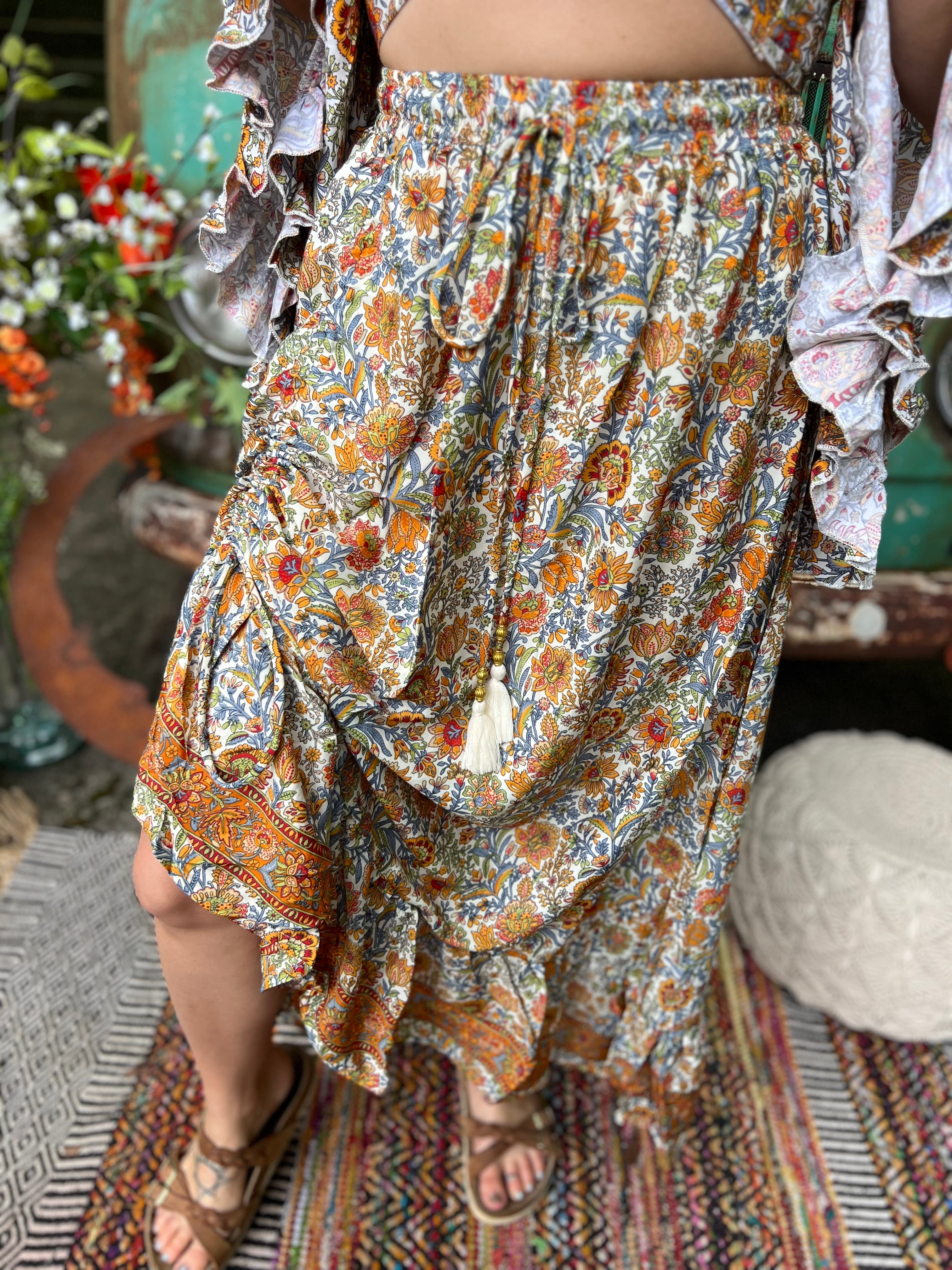 Someone wearing the orange & cream Hippie Floral Cinch Maxi Ruffle Skirt in front of a Volkswagen bus.