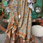 Someone wearing the orange & cream Hippie Floral Cinch Maxi Ruffle Skirt in front of a Volkswagen bus.