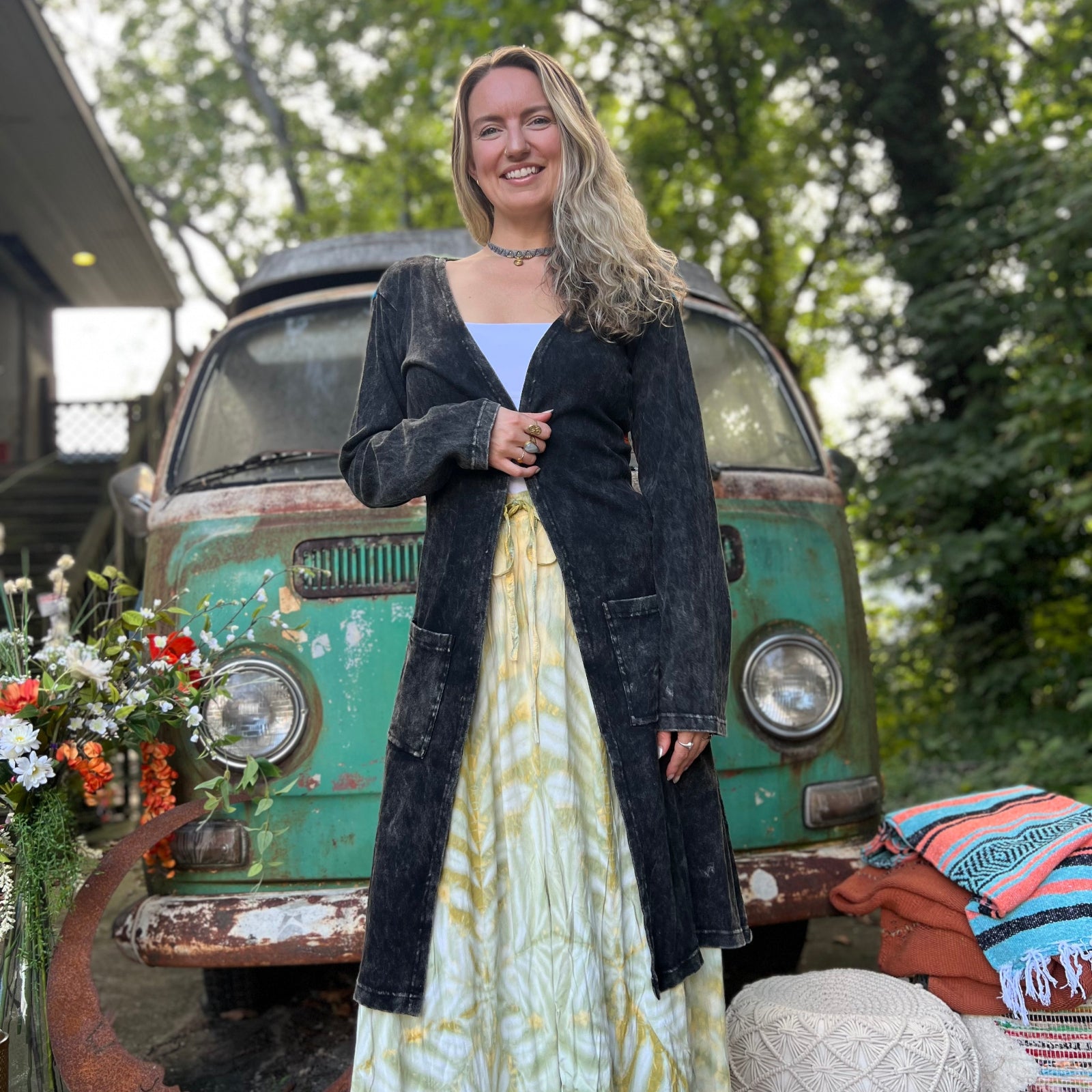 A woman wearing the black Sun Ray Cardigan in front of a vintage Volkswagen bus.