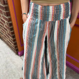 A woman wearing the playa Striped Wide Leg Cotton Pants with a tan top and sandals.