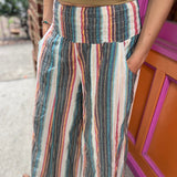 A woman wearing the playa Striped Wide Leg Cotton Pants with a tan top and sandals.