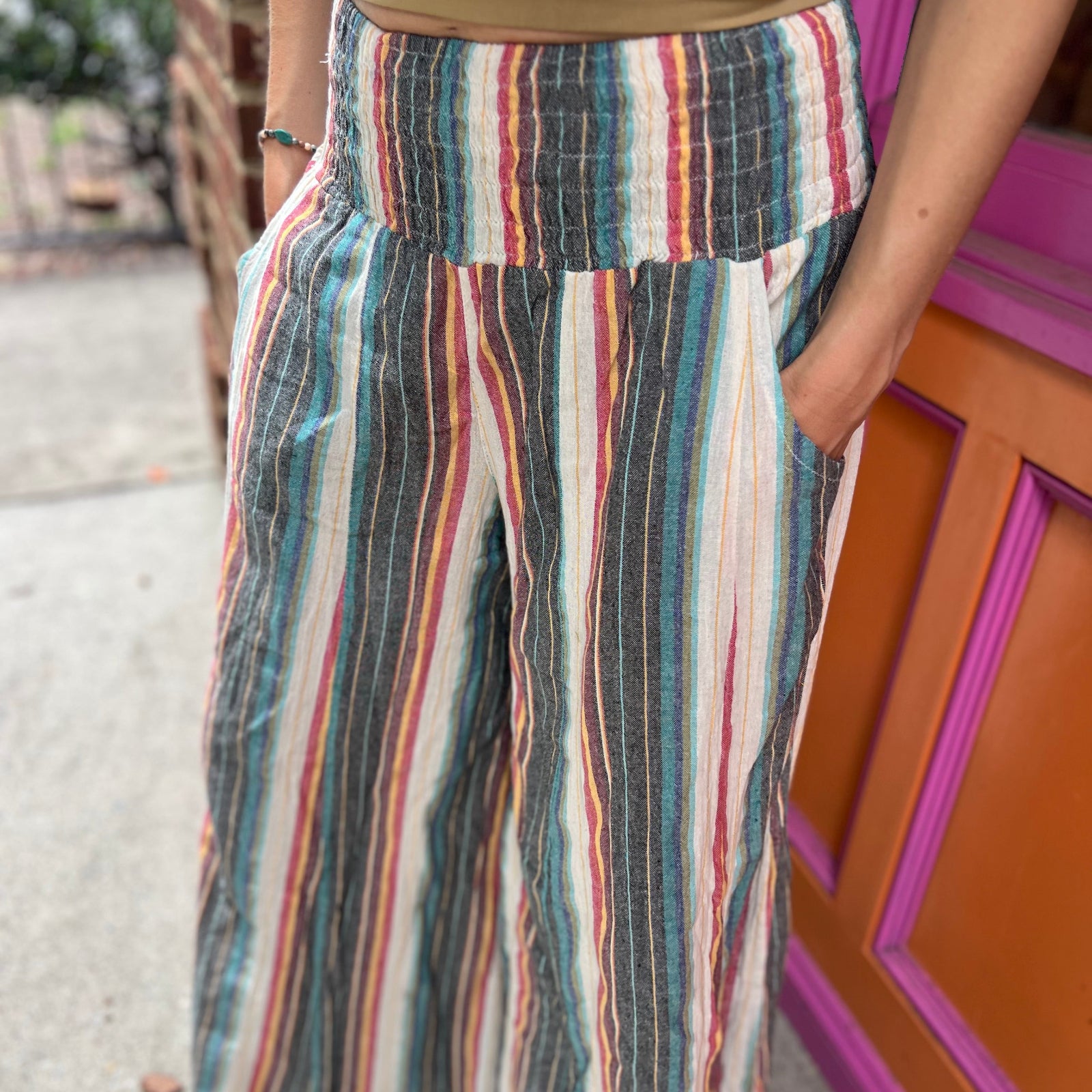 A woman wearing the playa Striped Wide Leg Cotton Pants with a tan top and sandals.