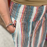 An up close image of a woman wearing the playa Striped Wide Leg Cotton Pants with a tan top and sandals.