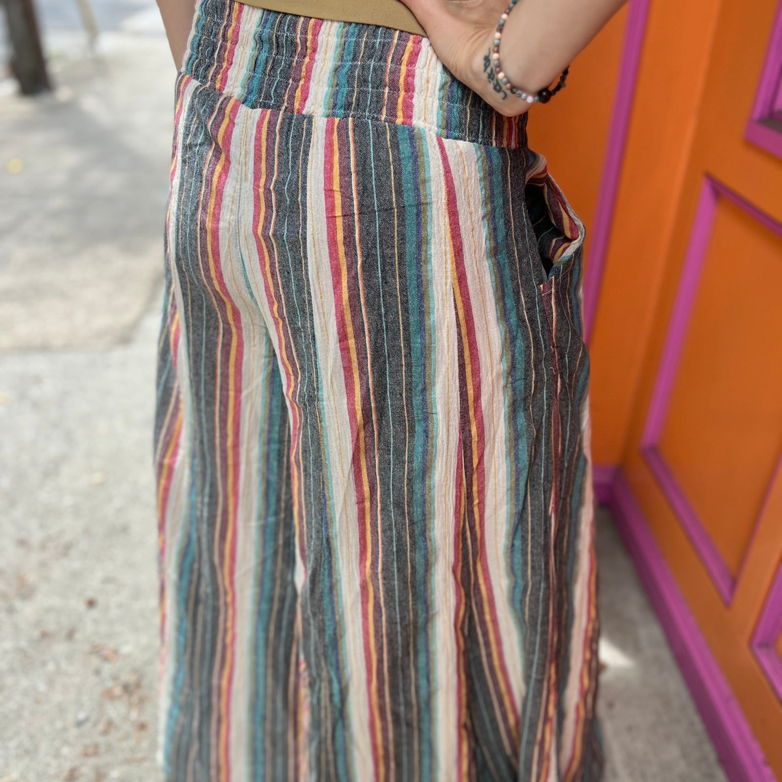 A woman wearing the playa Striped Wide Leg Cotton Pants with a tan top and sandals.