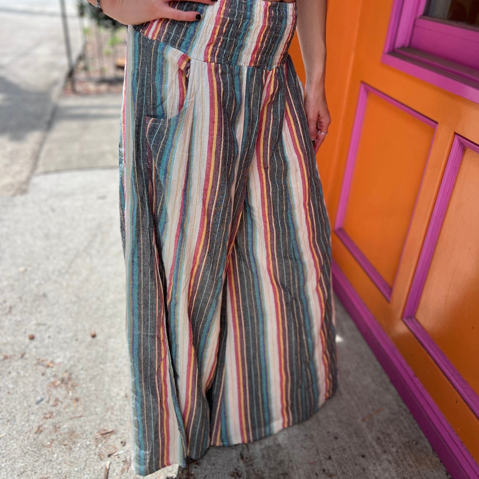 A woman wearing the playa Striped Wide Leg Cotton Pants with a tan top and sandals.