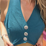 A woman wearing the blue Rustic Stripe Fitted Vest with a tan tank and striped pants.